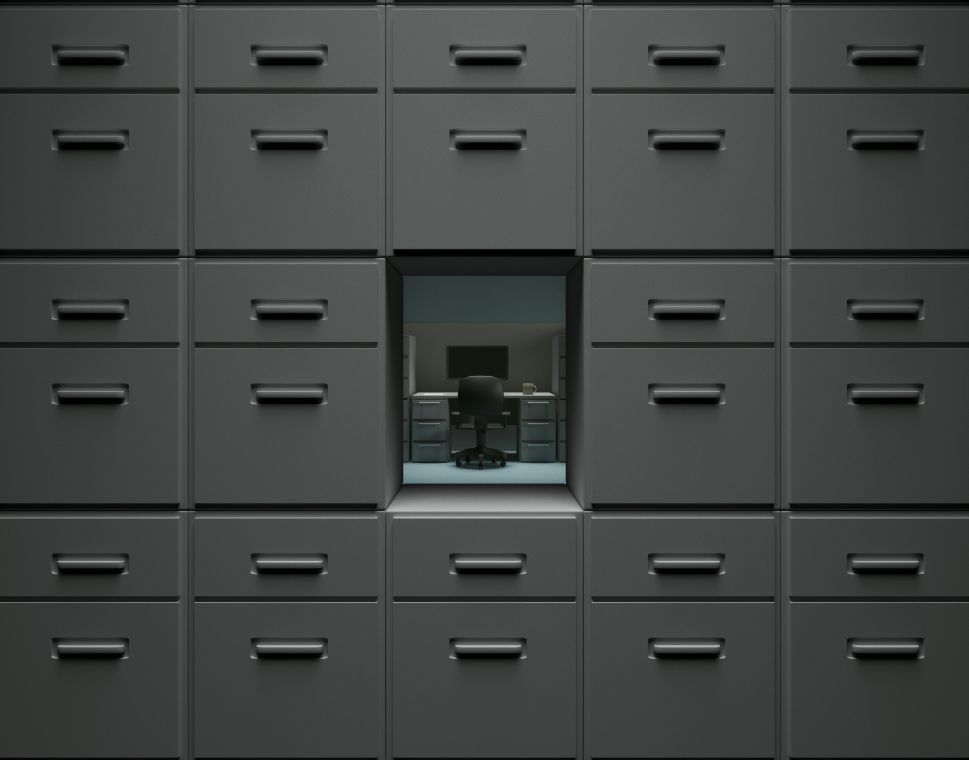 An empty office desk surrounded by filing cabinets