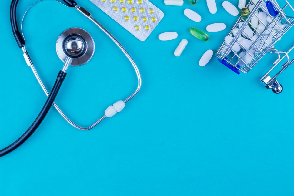 A stethoscope lays beside a small overturned shopping cart of pills