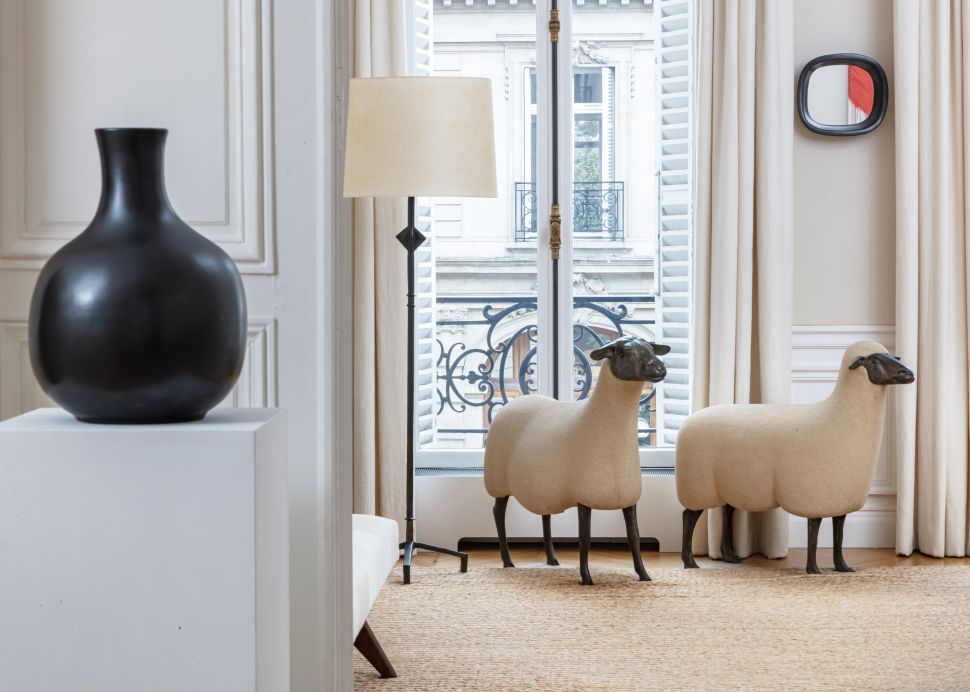 Paris apartment interior shows two François-Xavier Lalanne sheep sculptures beside a floor lamp, with a black vase on a plinth in the foreground