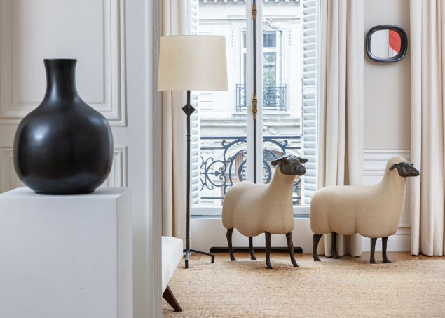 Paris apartment interior shows two François-Xavier Lalanne sheep sculptures beside a floor lamp, with a black vase on a plinth in the foreground