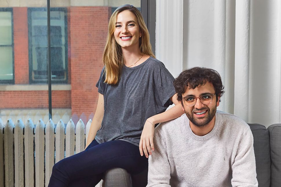 A blonde woman and a man posing for a photo in an office.