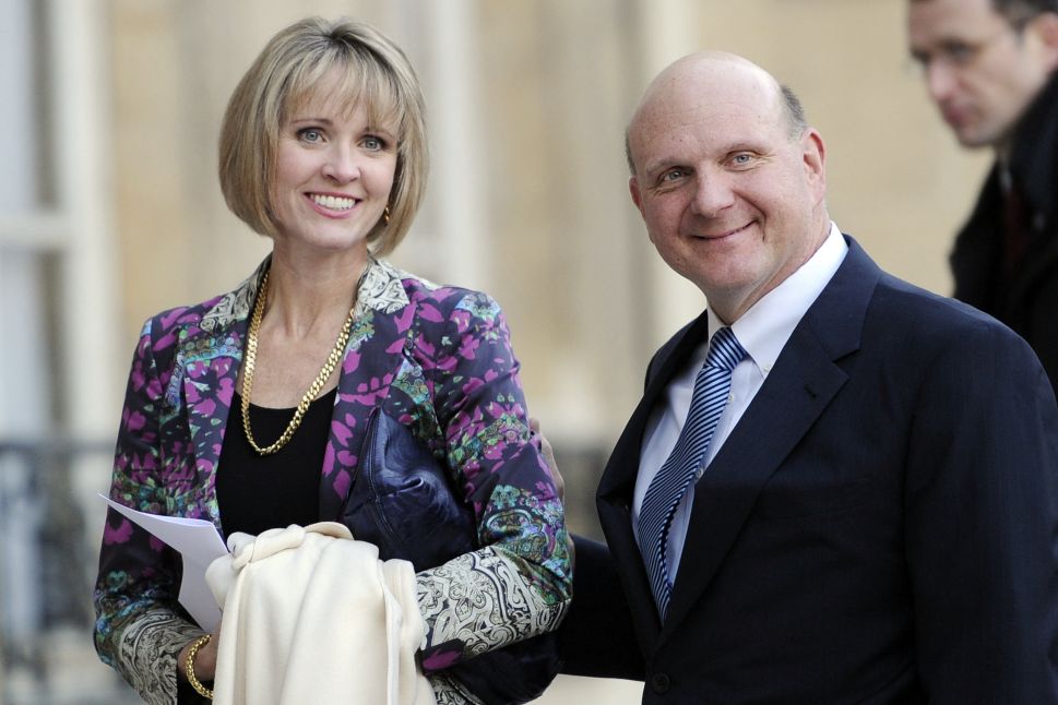 Woman in purple jacket and man in black suit pose outside