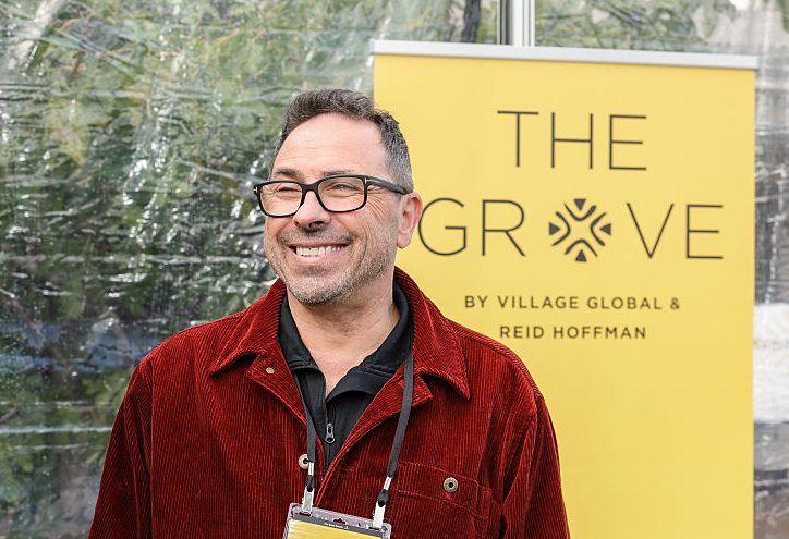 A man in a casual red jacket against a yellow background.