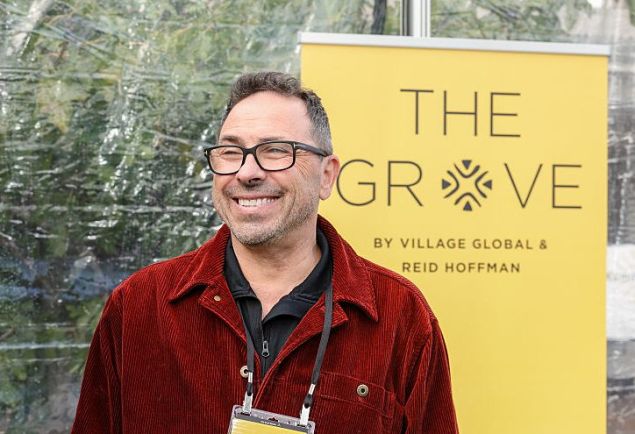 A man in a casual red jacket against a yellow background.