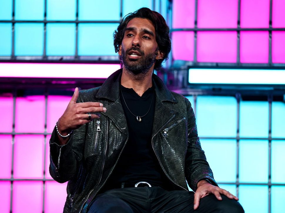 An Indian man wearing a black leather jacket speaking onstage