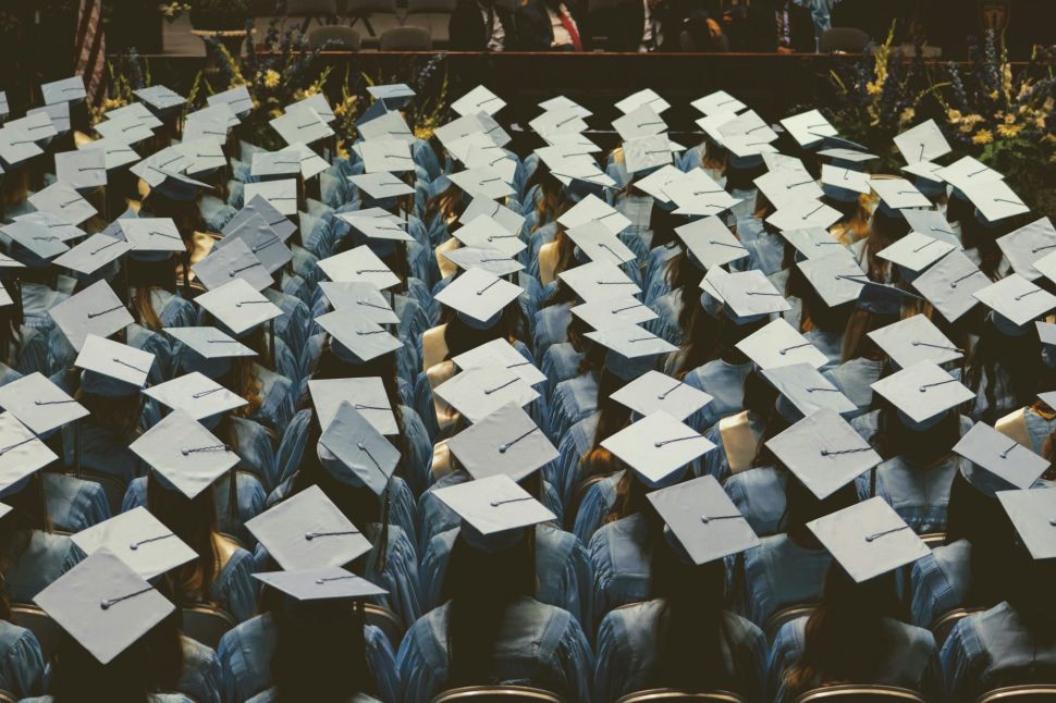 A crowd of graduating students at a commencement address wearing caps and gowns